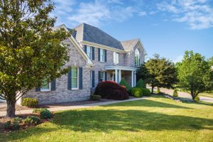 Suburban brick house with shrubs and trees along walkway